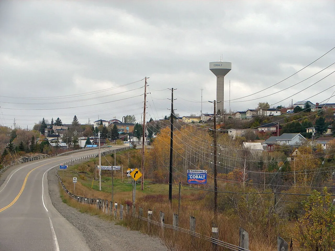 The highway into Cobalt curving down toward the town, with a Cobalt sign at the roadside and a water tower on the hill beyond.