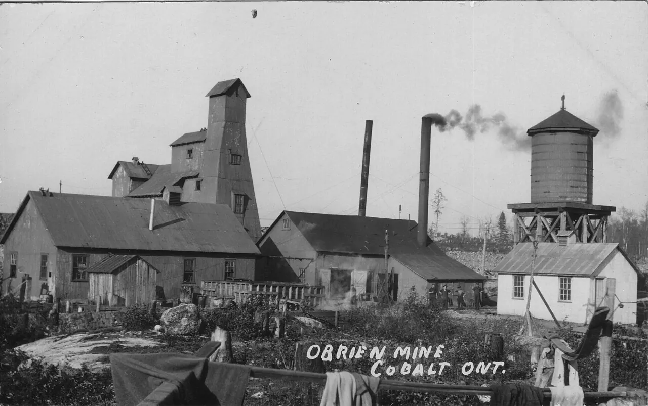 A postcard-era photograph of the O'Brien Mine at Cobalt: a wooden headframe, mill buildings and a water tank.