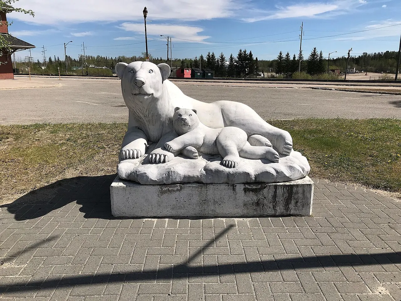 A white stone sculpture of a polar bear and cub in the plaza beside Cochrane's train station.
