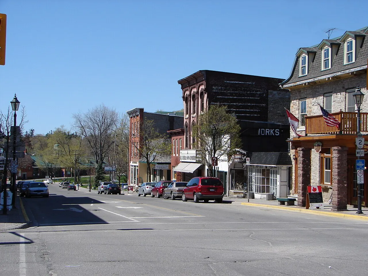 King Street in Gananoque, a wide small-town main street with brick storefronts and a hotel on the right.